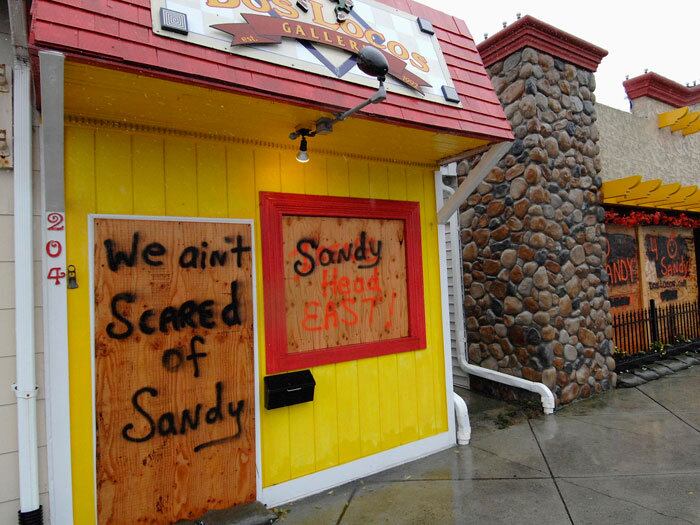 Casas comerciais cobrem suas portas e janelas para proteger o estabelecimento dos fortes ventos do furacão