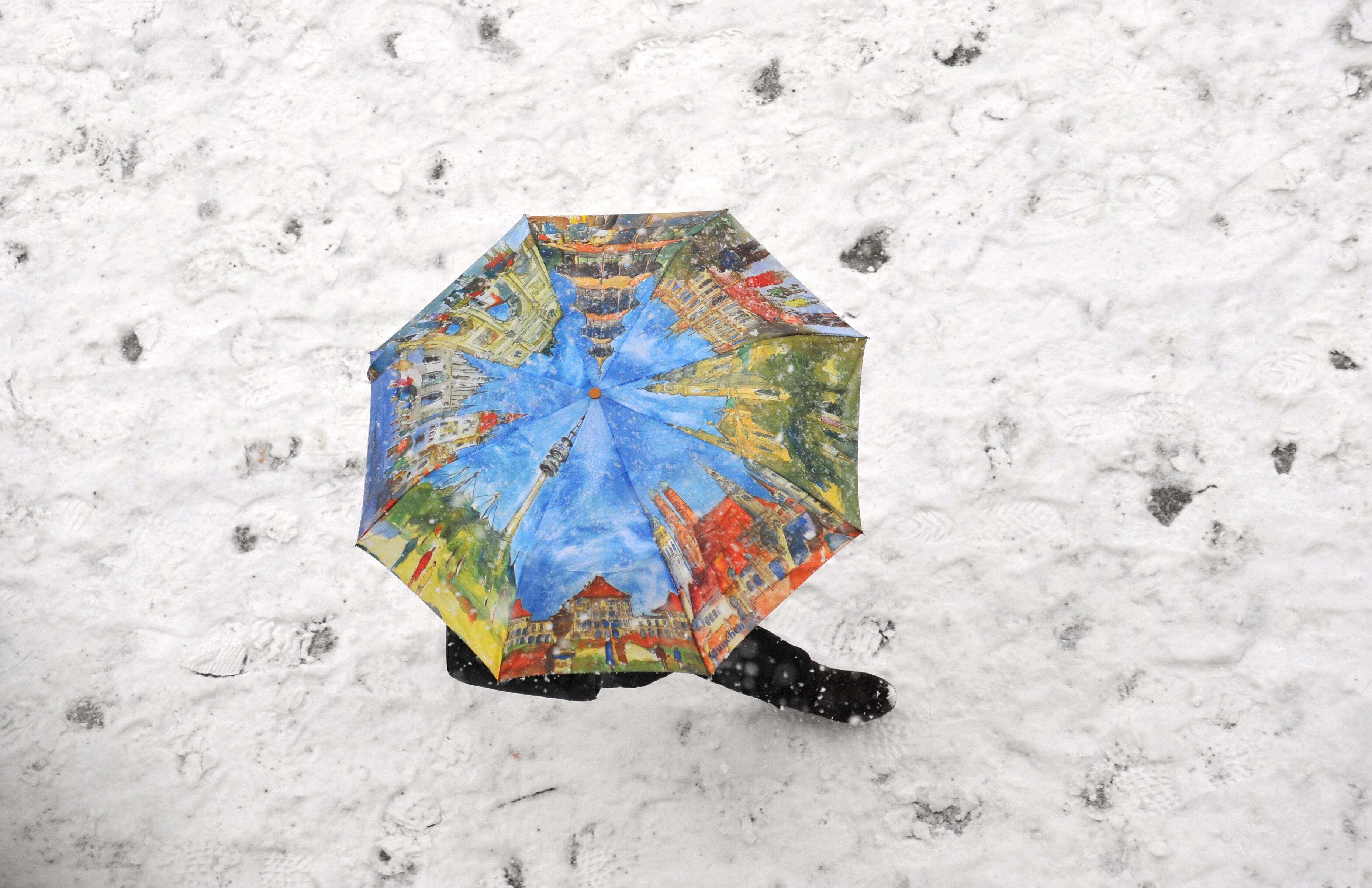Alemão usa guarda-chuva para caminhar em meio a tempestade de neve em Munique, na Alemanha
