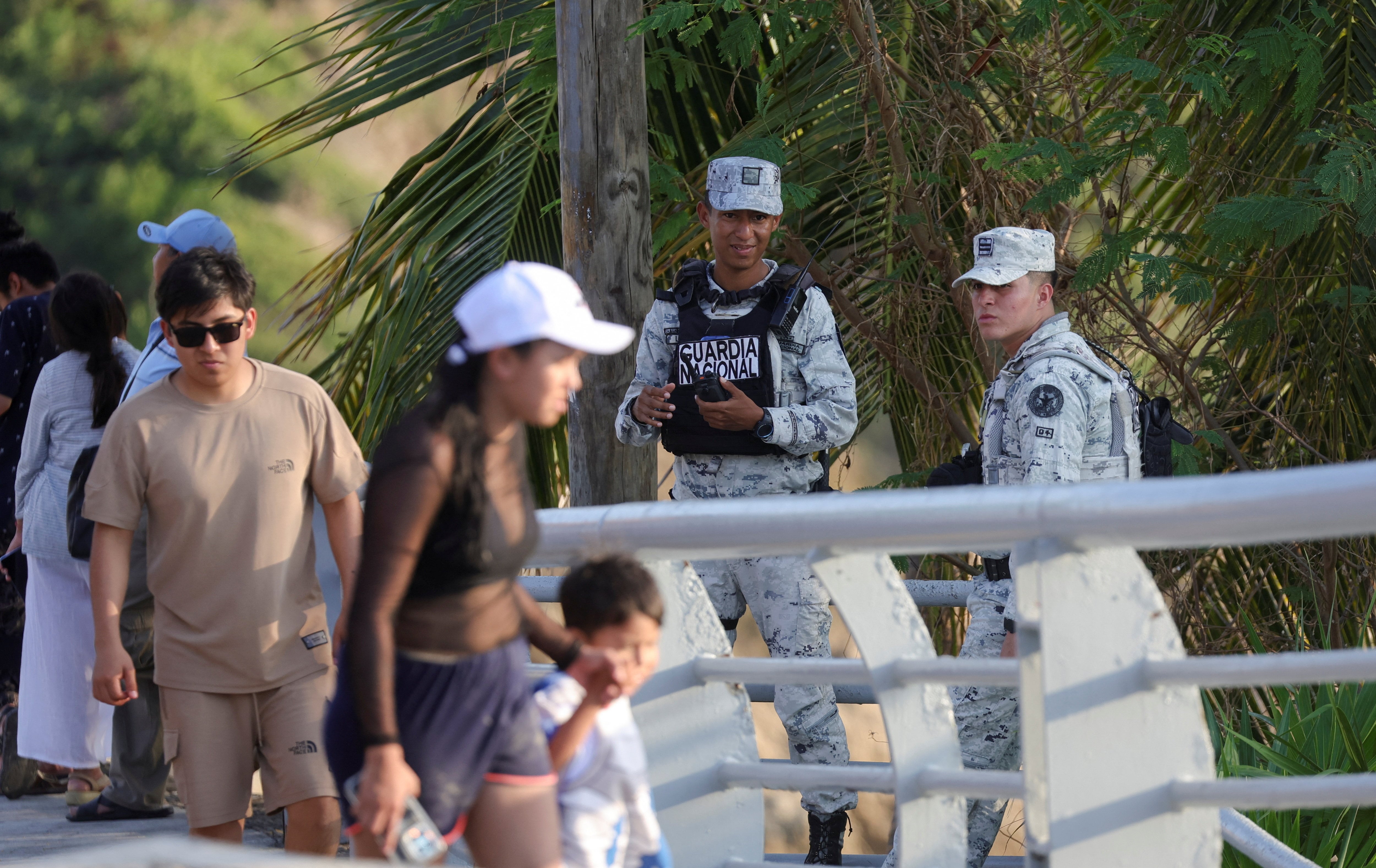 Pessoas passam por membros da Guarda Nacional em patrulha, depois que as autoridades reforçaram a segurança após bloqueios de estradas e ataques incendiários realizados pelo crime organizado.