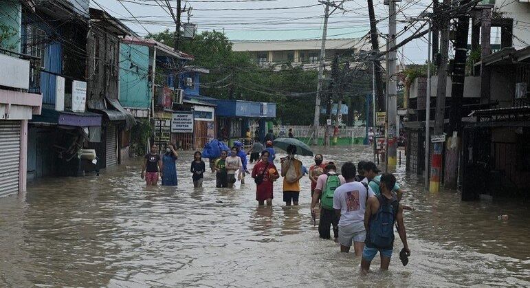 Pessoas caminham por rua inundada nas Filipinas após passagem da tempestade tropical Nalgae