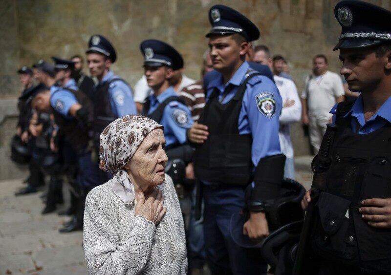 Devota passa por membros
do Ministério do Interior em frente ao monastério de Pechersk Lavra, em Kiev,
no dia da eleição de líder da Igreja Ortodoxa Ucraniana