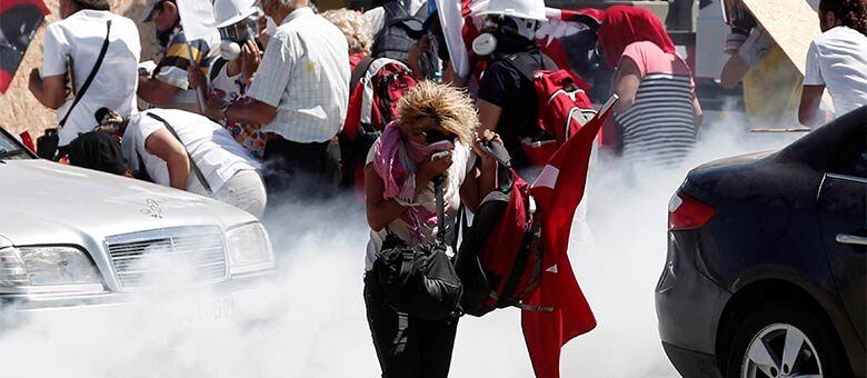 Mulher foge de bombas de gás atiradas pela polícia em frente ao tribunal de Silivri, perto de Istambul, onde supostos golpistas contra o governo de Erdogan foram condenados