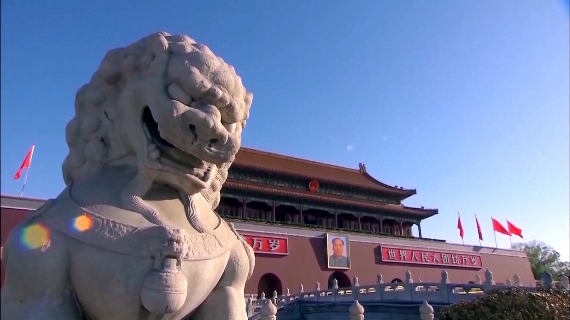 Estátua de pedra diante de um edifício histórico com bandeiras vermelhas na China