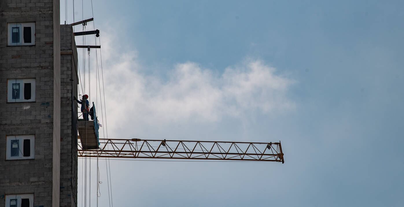 Operário da construção civil faz retoque em fachada de edifício em SP
