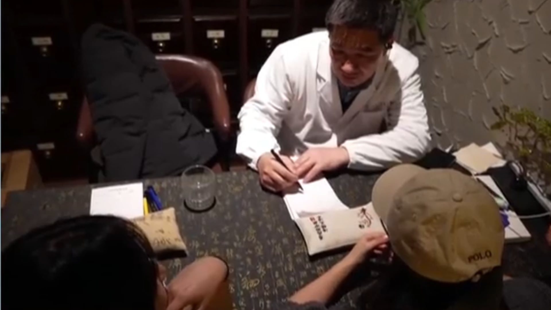 Jovens se consultam antes de pedirem drinks em bar de medicina tradicional chinesa