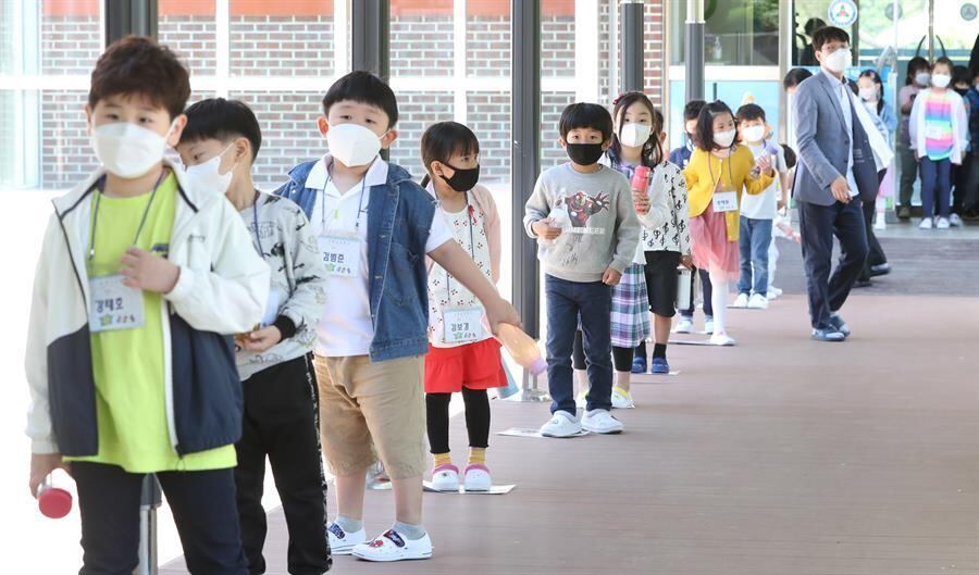 Crianças fazem fila usando máscaras e observando o distanciamento social em escola primária na Coreia do Sul, que retomou as aulas nesta quarta (27 de maio)