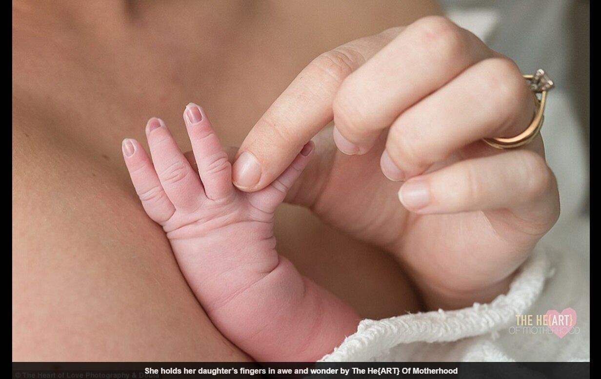 Uma mãe segura os pequenos dedinhos de seu bebê

