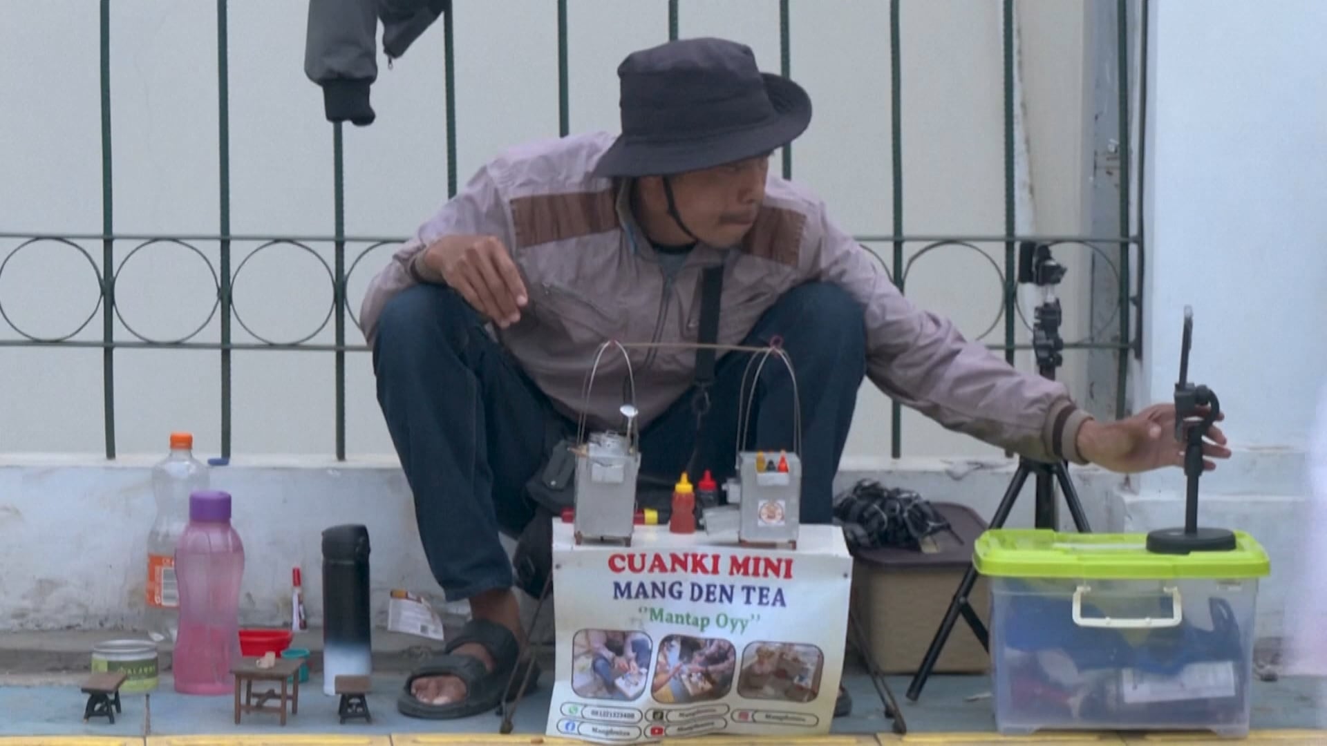 Homem sentado vende miniatura de comida na Indonésia e faz transmissões ao vivo nas redes sociais
