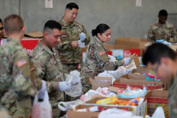 Tropas da Guarda Nacional da Califórnia empacotam sacos de alimentos para ajudar trabalhadores voluntários idosos em confinamento em casa no FIND Food Bank durante os esforços da doença por coronavírus em Indio