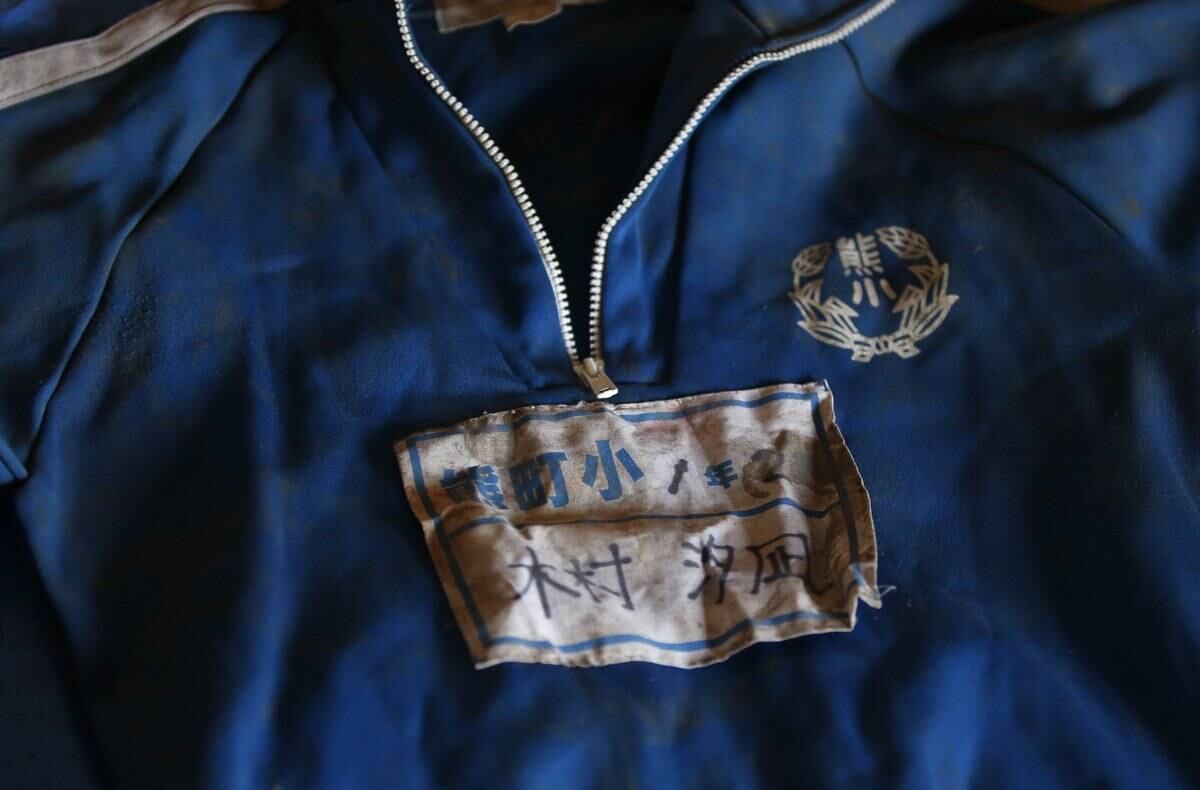 Este é o uniforme
escolar da pequena Yuna Kimura, morta no tsunami que assolou o Japão em 2011. O
agasalho está dentro de um templo localizado na zona de exclusão de Okuma. A
etiqueta traz os seguintes dizeres: “Kumamachi Elementary School, First Grade
Second Class, Yuna Kimura” (Escola Elementar de Kumamachi, Primeiro grau da
segunda classe, Yuna Kimura)