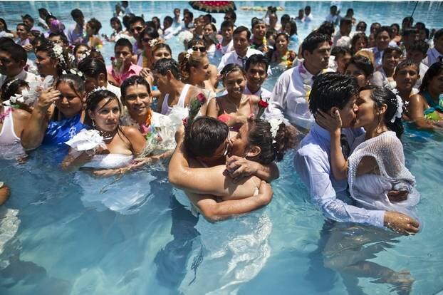 Esse beijo coletivo aconteceu dentro de uma piscina pública durante um casamento em massa no Dia dos Namorados em Lima, Peru. Mais de 200 casais participaram de um casamento civil

