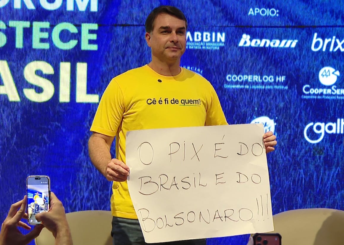 Senador Flávio Bolsonaro segura cartaz em evento de pré-campanha