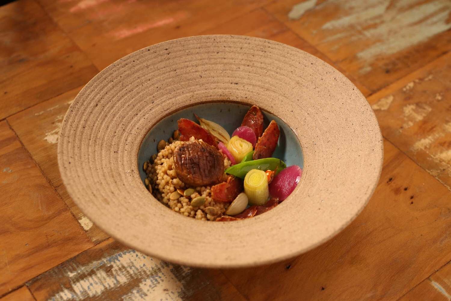 Mine Arroz de Cogumelos e Sementes de Abóbora 
Por Antonio Filho (Tony)

Ingredientes:
1 xícara de arroz ½ xícara de sementes de abóbora sem pele 
50 mil de azeite  
6 unidades de cogumelo shitake  
40 g de cogumelo porcini seco  
2 xícaras de ervilha torta
½ xícara de linguiça defumada
3 colheres (sopa) de cebola roxa
2 colheres (sopa) de manteiga
Sal e pimenta a gosto  

Preparo: 

Lave bem a porção de cogumelo porcini seco e hidrate com 1 litro e meio de água fervente. Depois, pique bem miúdo e reserve o caldo do cozimento. Em uma frigideira larga, toste as sementes de abóbora com um pouco de manteiga, tempere com sal e pimenta, e reserve. Com a mesma frigideira, acrescente um fio de azeite e um pouco de manteiga para refogar rapidamente os cogumelos shitake inteiros. Reserve. Faça o mesmo procedimento com a ervilha torta e reserve. Em seguida, frite os cubos de linguiça com azeite, acrescente a cebola roxa e o porcini picado. Acrescente o mini arroz e o caldo do cozimento do porcini aos poucos, até que o arroz cozinhe. Para finalizar, adicione o sal ao caldo.  


