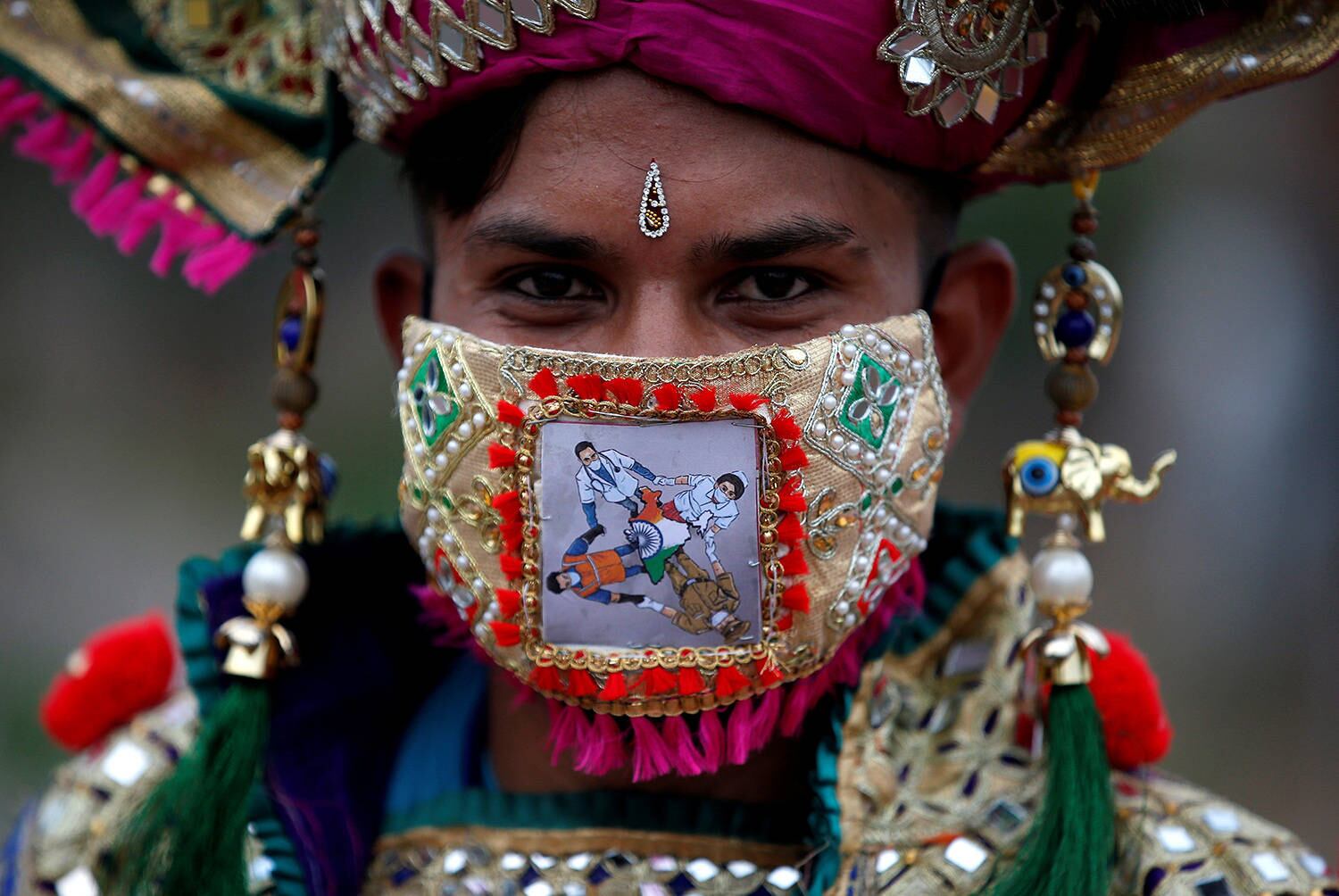 A participant in traditional costume wearing a mask featuring "COVID-19 warriors" as he attends a rehearsal for Garba, a folk dance, ahead of Navratri, a festival during which devotees worship the Hindu goddess Durga and youths dance in traditional costumes, amidst the coronavirus disease outbreak, in Ahmedabad, India, September 18, 2020. REUTERS/Amit Dave TPX IMAGES OF THE DAY