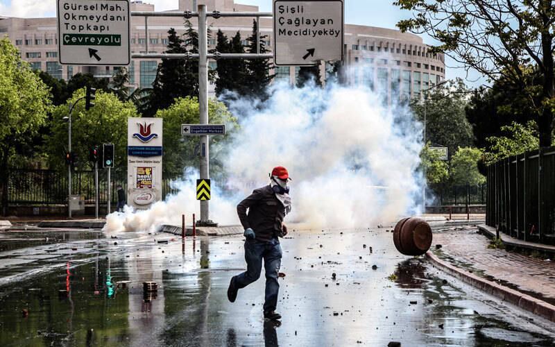 Manifestante mascarado corre de bomba de gás atirada pela polícia de Istambul, na Turquia, em protesto no Dia do Trabalho. A polícia turca usou jatos de água e bombas de gás para dispersar milhares de protestantes que tentaram desafiar a probição de manifestação no Dia do Trabalho na Praça Taksim. O local foi palco de diversas manifestações anti-governo nos últimos meses