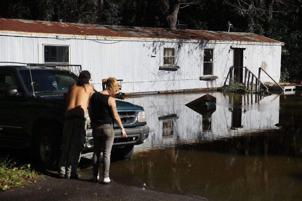Kimberlee Bashford e Jorge Valenciaga, moradores de Spring Lake, na Carolina do Norte, observam a água que já tomava conta da sua propriedade em Spring Lake, a 17 quilômetros de Fayeteville, nesta terça-feira (18)

