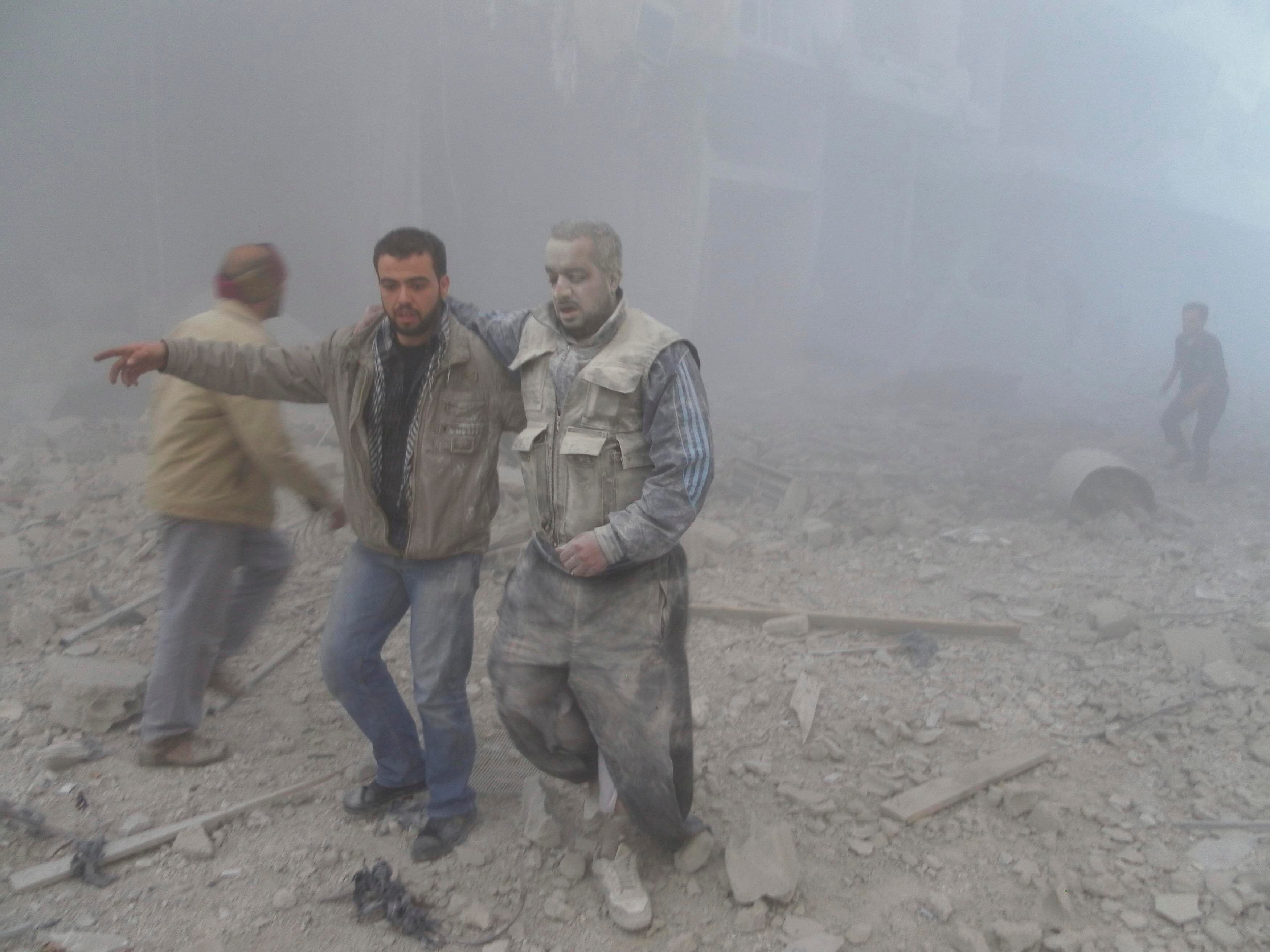 Rebeldes sírios são fotografados perto de prédios destruídos por bombardeios. Ativistas afirmam que o Exército sírio lançou mísseis no bairro de Akraba, em Damasco