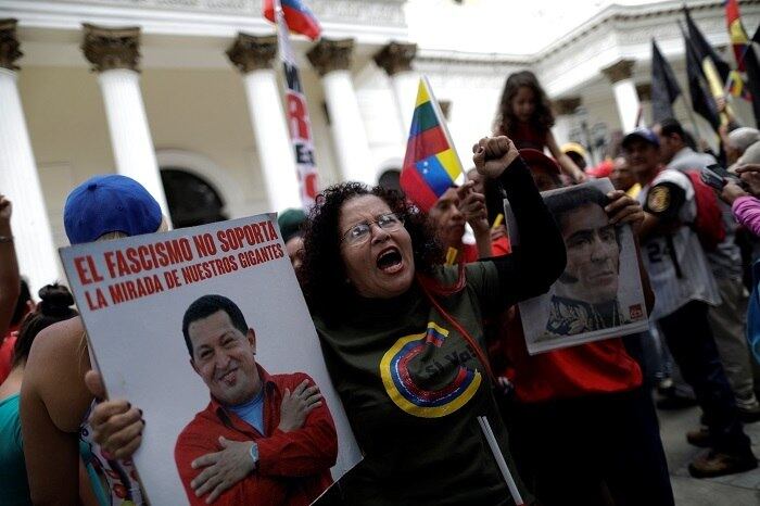 Nas mãos, os apoiadores de Maduro carregam cartazes com imagens do ex-presidente Hugo Chávez e de Simón Bolívar, considerado um herói pelos venezuelanos