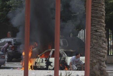 Morador se esconde atrás de carro incendiado durante o confronto