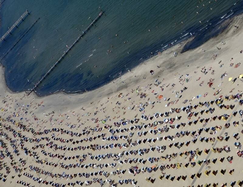 Pessoas tomam sol em praia em Travemuende,
na Alemanha, no Mar Báltico