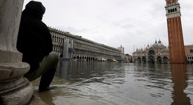 Homem observa Praça de São Marcos inundada em Veneza