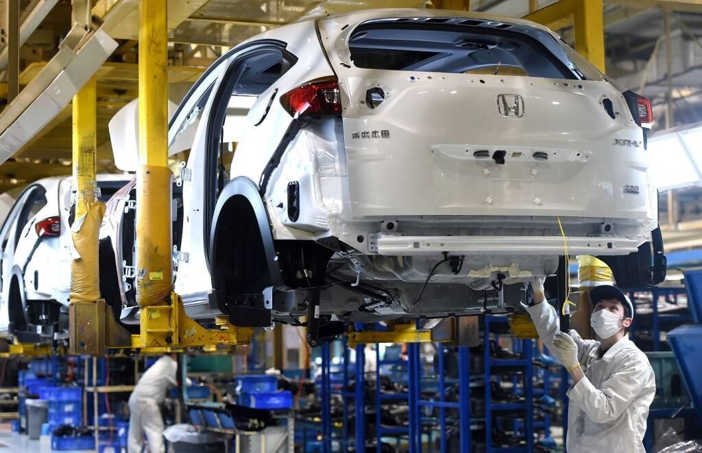 Funcionário de máscara na linha de produção da Honda na China: novos tempos