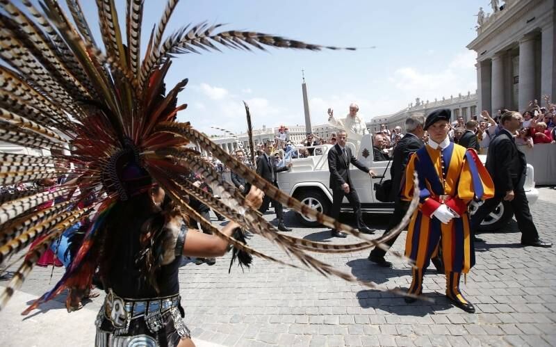 O Papa Francisco acena
para os fiés ao deixar a Praça de São Pedro, ao mesmo tempo em que membros do
Festival Internacional de Grupos Tribais e Indígenas se apresentam no local com
roupas típicas