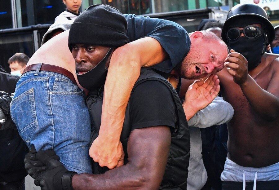 Patrick Hutchinson carrega manifestante para fora de confusão no sábado
