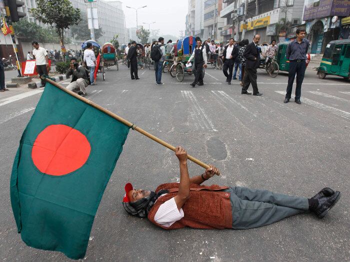 

Ativista do Partido Comunista de Bangladesh (CPB) segura a
bandeira de Bangladesh deitado na rua durante uma greve em Dhaka

