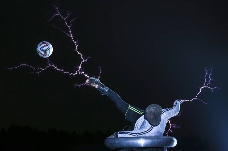 Membro do grupo Thunderbolt Craziness
chuta uma bola de futebol enquanto eletricidade é lançada de seu corpo durante
apresentação em Changle, na China, para celebrar a Copa do Mundo