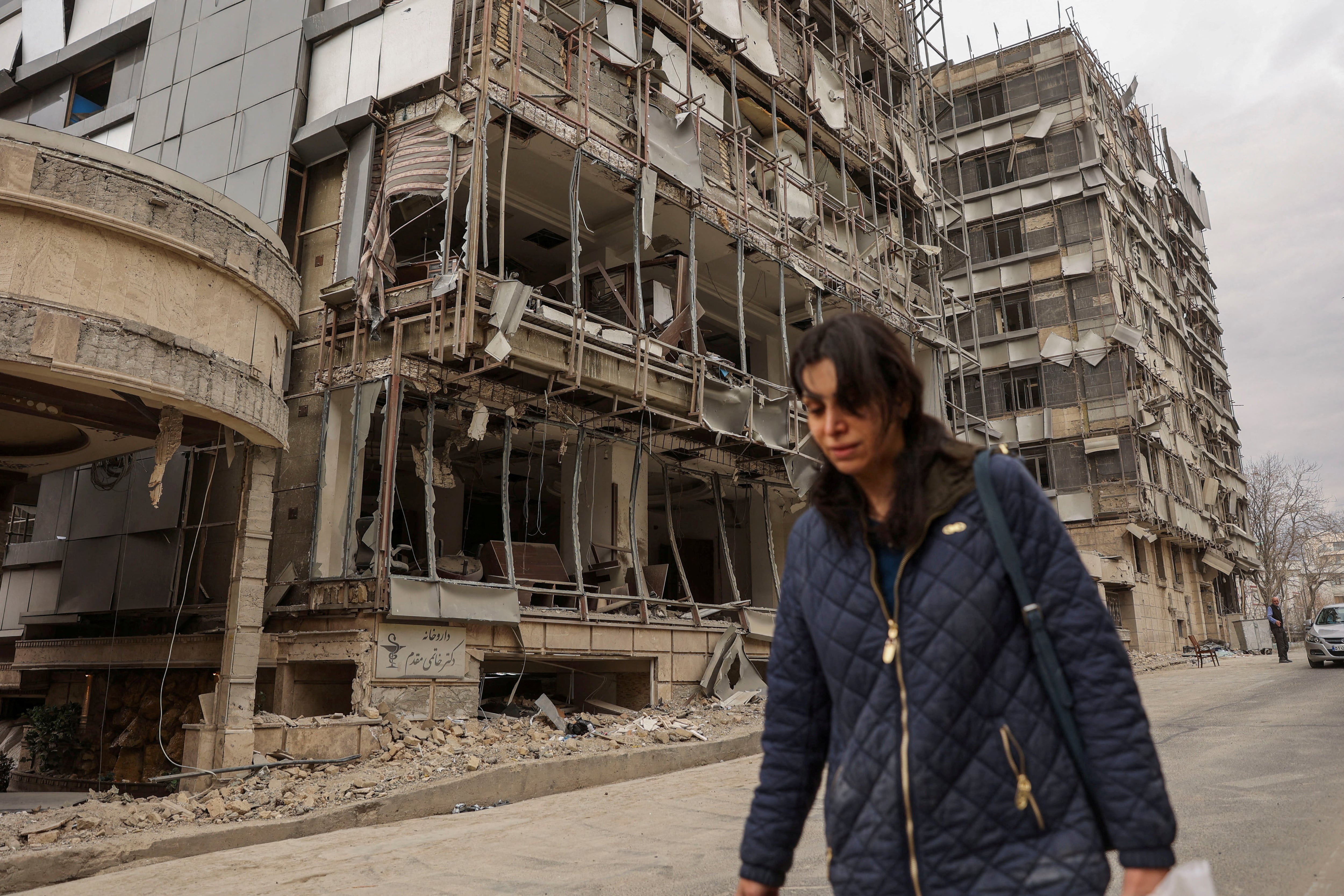 Mulher caminha após ataque israelense e norte-americano ao Hospital Hotel Gandhi em Teerã, Irã