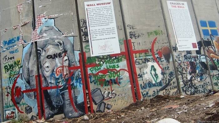 A barreira de concreto já foi bastante questionada pela comunidade internacional. Nesse trecho, um rinoceronte corre e rompe o muro