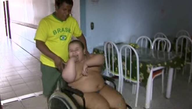 O garoto precisa usar fraldas e é transportado em uma cadeira de rodas. Para que a criança não passe o dia todo deitada, o pai o leva para passear em uma cadeira de rodas todos os dias
