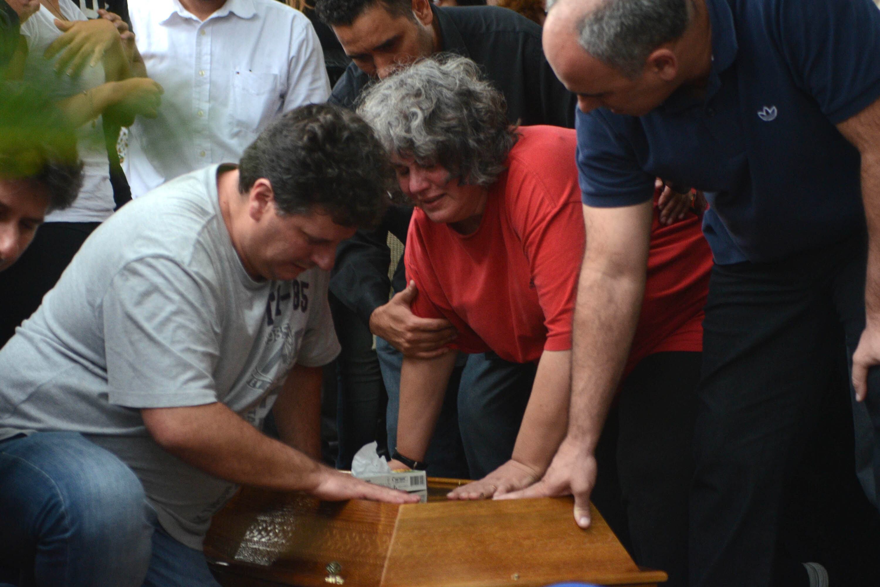 Mãe de estudante é consolada por parente durante enterro