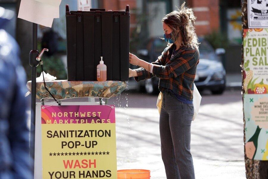 Mulher higieniza as mãos ao chegar a feira livre em Seattle, nos EUA

