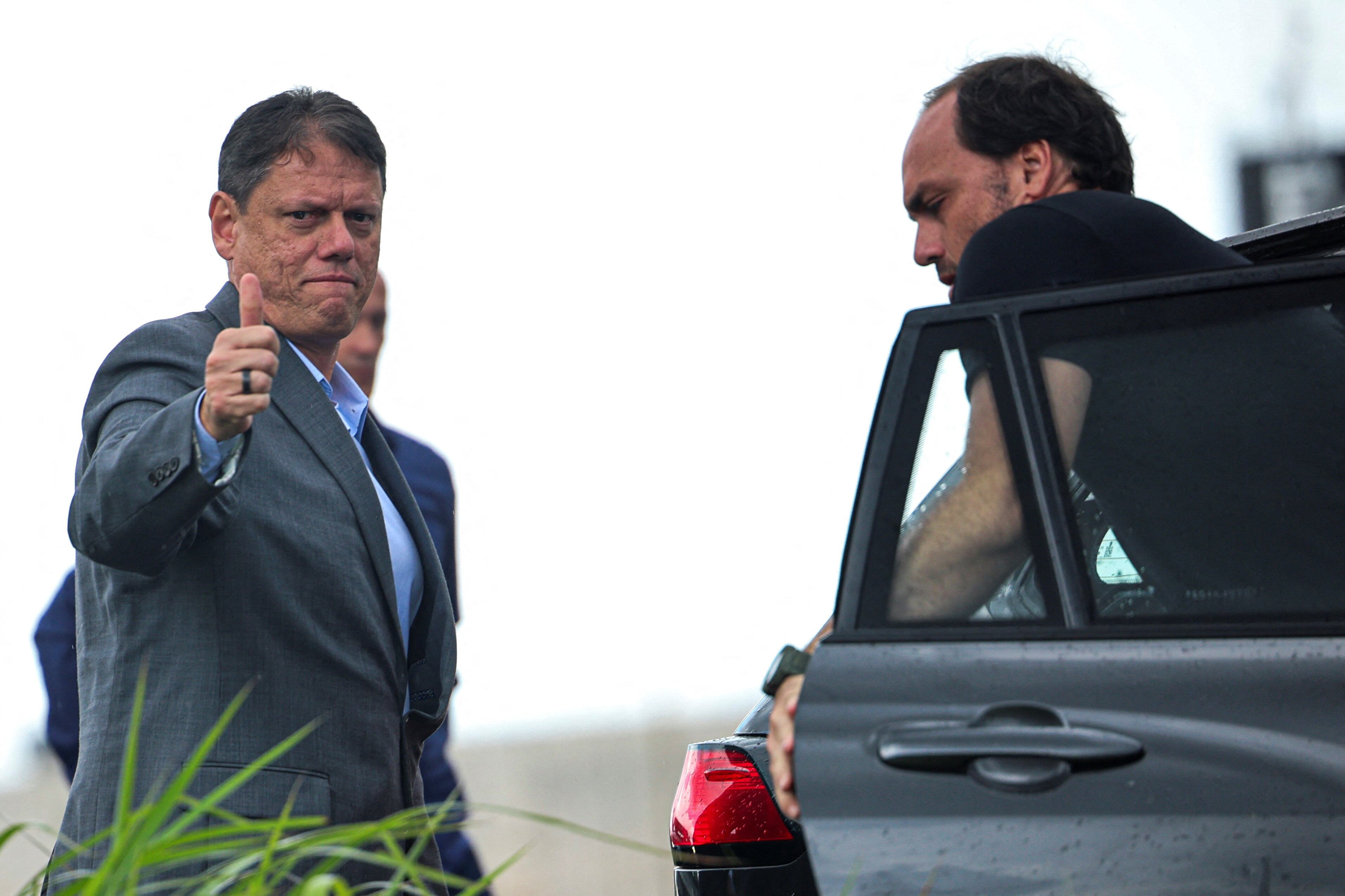 Sao Paulo's Governor Tarcisio de Freitas gestures as Carlos Bolsonaro, son of Brazil's former President Jair Bolsonaro steps out of a car before a press conference at the Papuda Penitentiary Complex after visiting former Brazilian President Jair Bolsonaro, who was convicted by a Supreme Court majority of plotting a coup to remain in power after losing the 2022 election, in Brasilia, Brazil, January 29, 2026. REUTERS/Adriano Machado