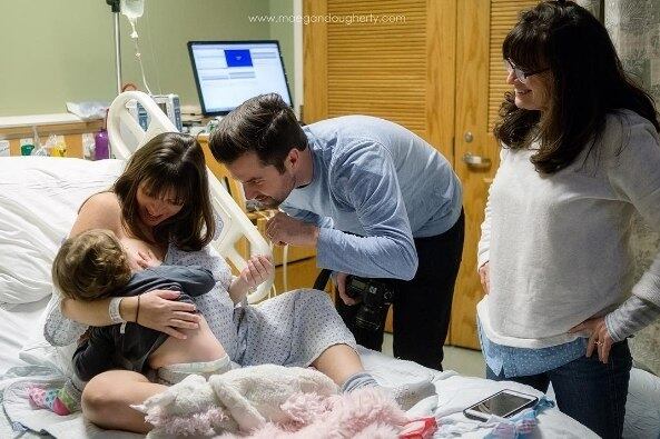 A fotógrafa especializada em parto Maegan Dougherty capturou o momento em que uma mãe tendo contrações no hospital amamenta sua primeira filha. A mãe estava em trabalho de parto no hospital quando a avó da criança chegou com a menina, que tem dois anos. A mãe prontamente se dispôs a alimentar sua primogênita