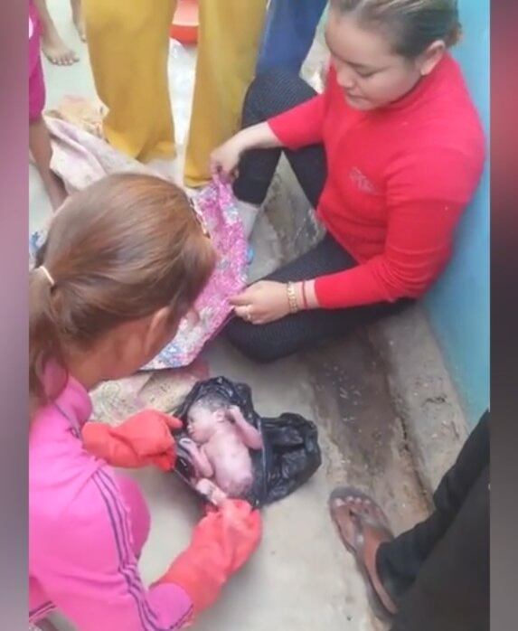 Uma outra mulher estende um cobertor ao lado, onde o bebê é colocado cuidadosamente