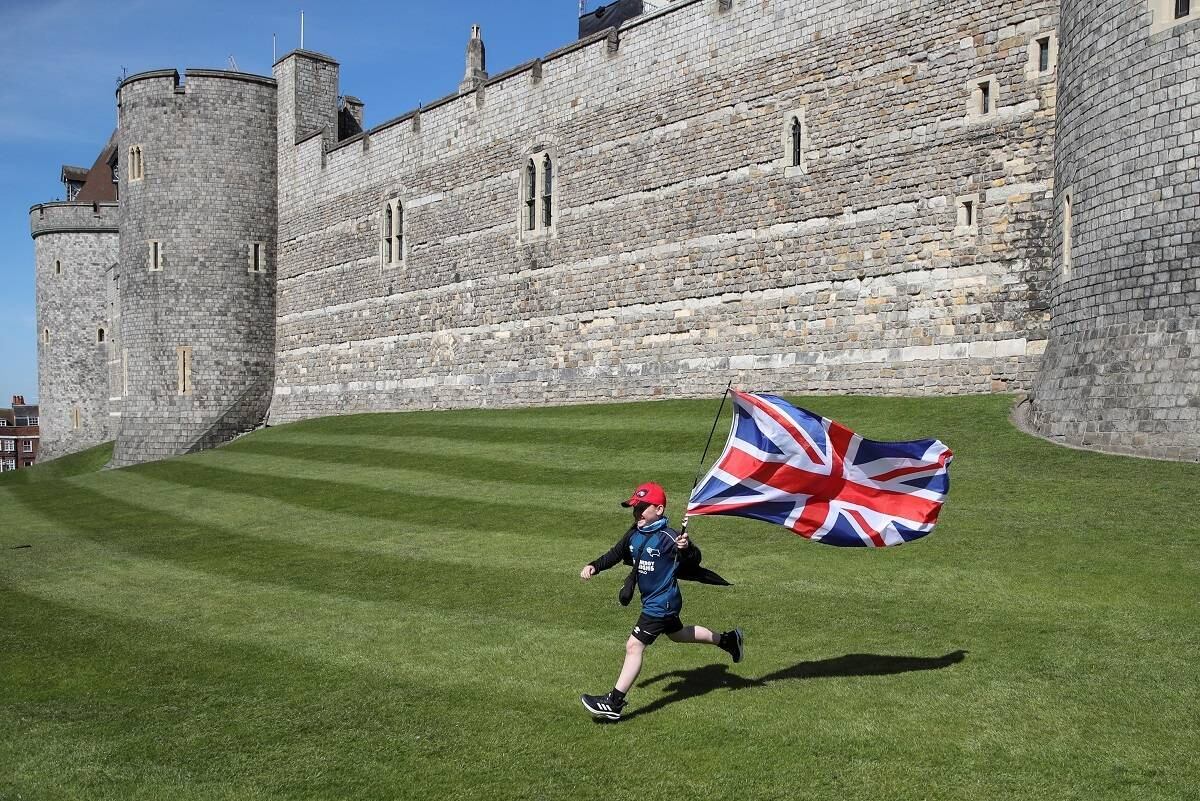 Na foto, Jayden Lucas, de 8 anos, corre do lado de fora do castrelo com uma bandeira do país