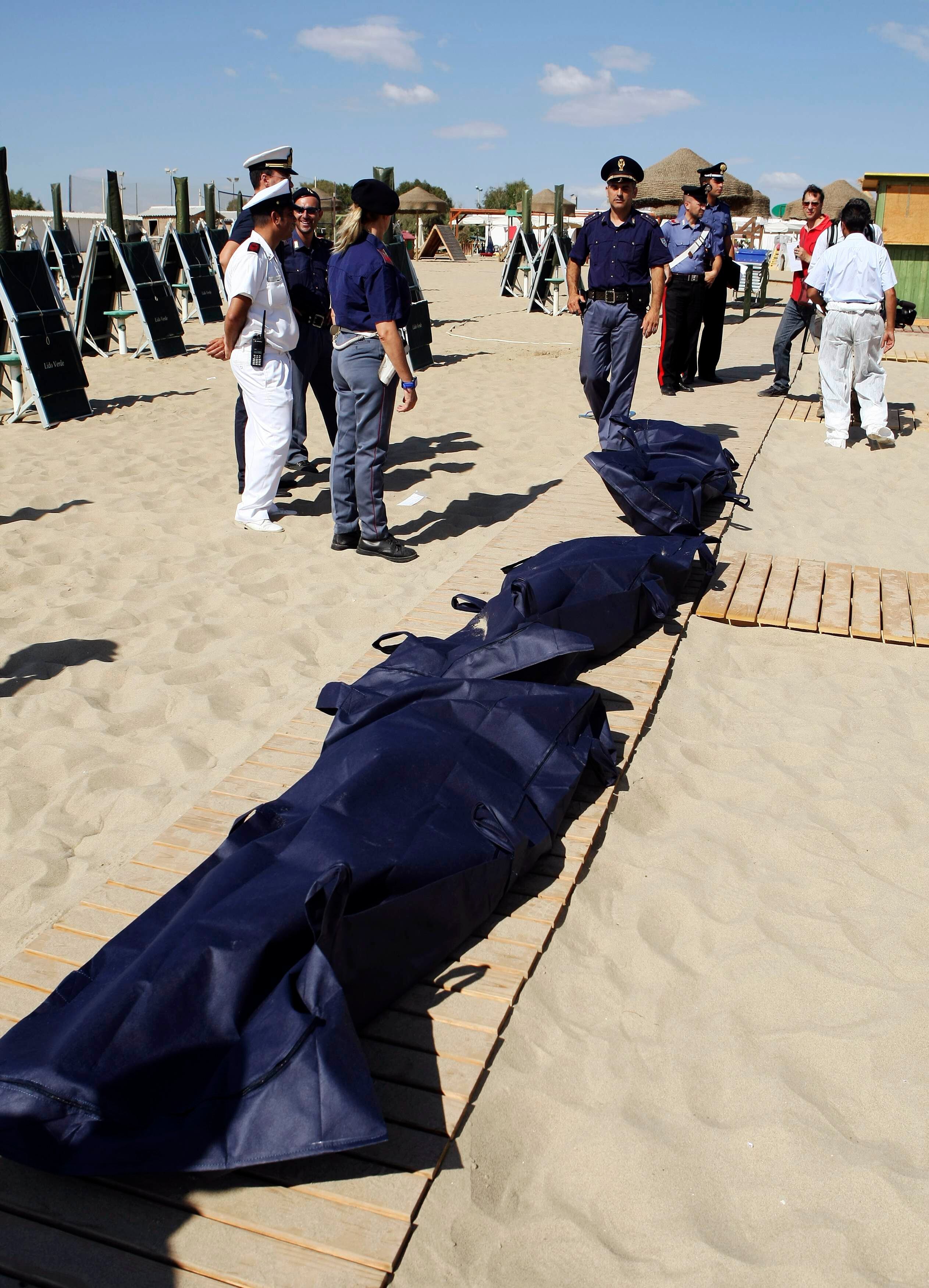 Polícia italiana monta guarda ao lado dos corpos dos imigrantes que se afogaram na praia de Catânia, na Sicília