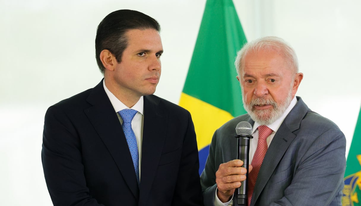 Hugo Motta e Lula com uma bandeira do Brasil ao fundo