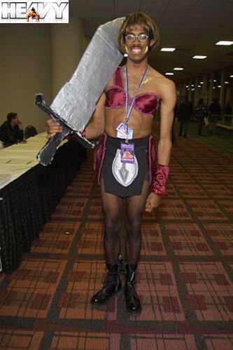 Pra quê uma espada tão grande? A gente responde: quando o sujeito resolve se vestir de mulher, ele tem que arrumar um outro jeito de mostrar que é espada, minha gente!