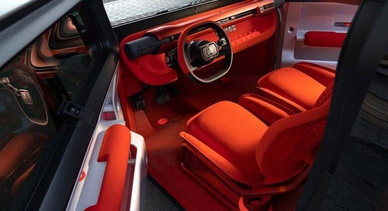Por dentro, a Oli traz um tom vermelho alaranjado nos bancos, tapetes e painel