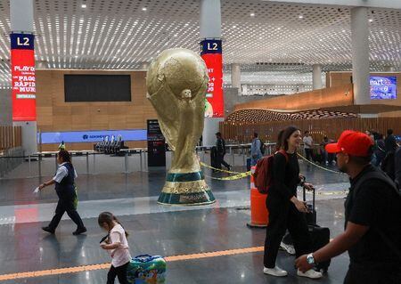 Passageiros passam por réplica gigante do troféu da Copa do Mundo no Aeroporto Internacional da Cidade do México