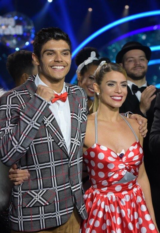 Bia Feres e Paulo Victor representaram muito bem o tempo da brilhantina! Usando maquiagem marcante, a atleta apostou em um vestido vermelho de frente única, enquanto seu parceiro de dança usou um terno com estampa de xadrez