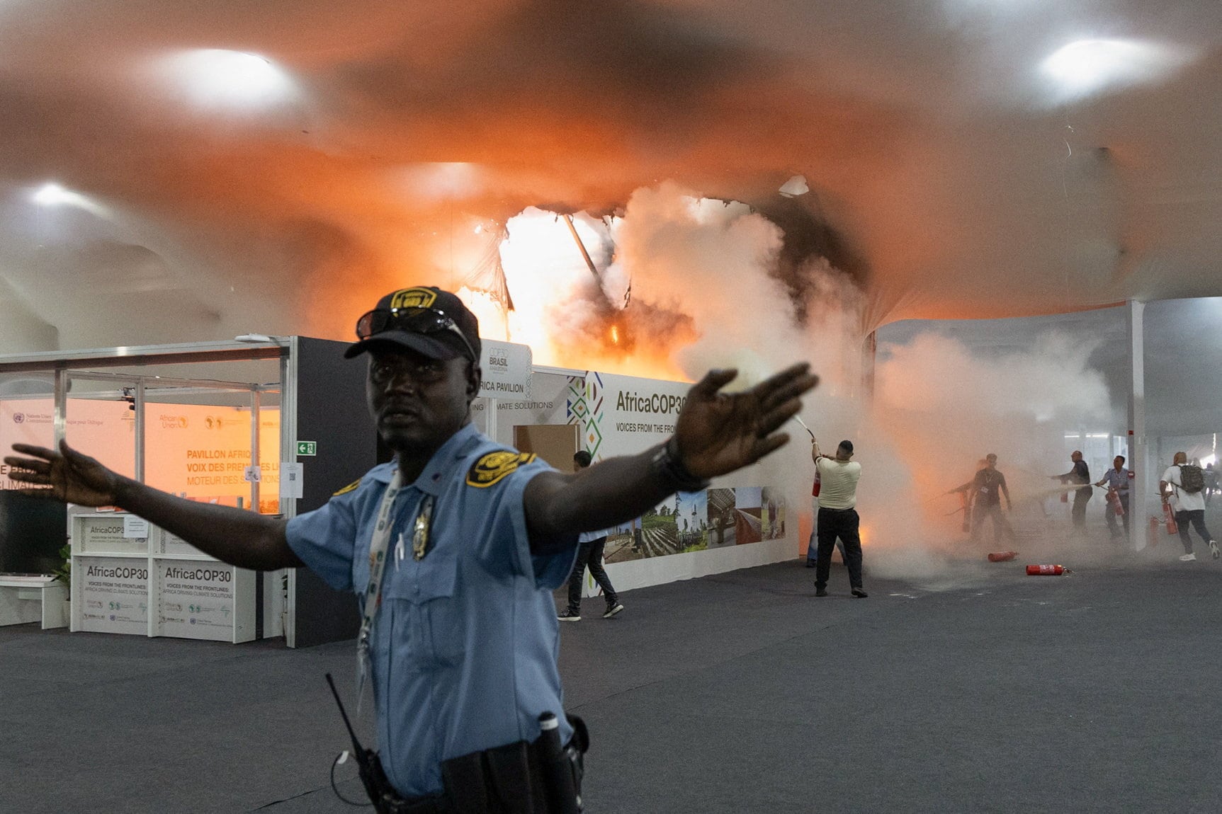 A security guard gestures as people use fire extinguishers to put out a fire at the Pavilion of Countries in the Blue Zone at the United Nations Climate Change Conference (COP30) in Belem, Brazil, November 20, 2025. REUTERS/Douglas Pingituro
