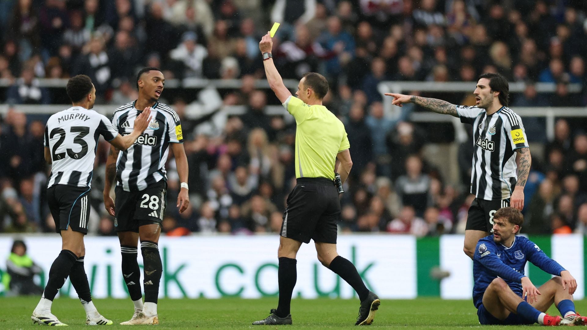 Árbitro dá cartão amarelo para jogador em partida entre Newcastle e Everton