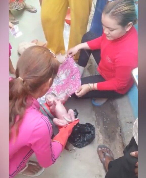 Em seguida, a mulher rasga o saco preto no qual o bebê foi abandonado