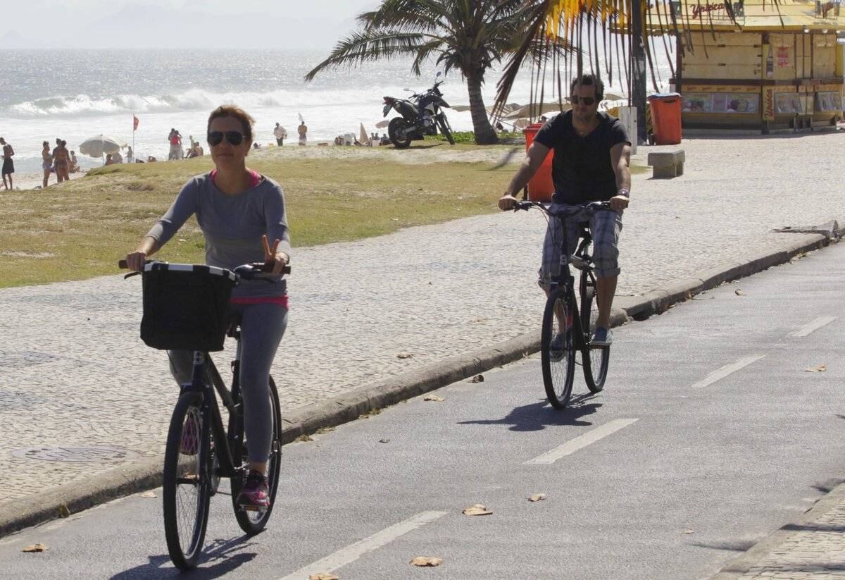 Adriana Esteves e Vladimir Britcha andam de bicicleta na praia da Barra, no Rio