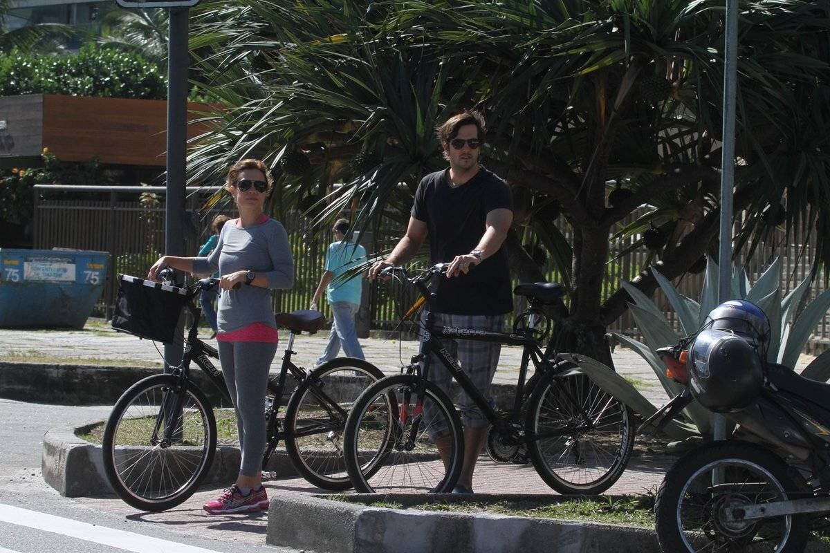 Adriana Esteves e Vladimir Britcha andam de bicicleta na praia da Barra, no Rio